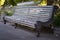 An old gray bench with peeling paint, into the park. Horizontal frame