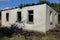 Old gray burnt brick house with empty black windows