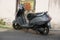 An old gray colored TVS Jupiter scooter parked outside a house. Two-wheeler is parked at road side in India. : Udapur India - July