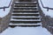 Old gray concrete staircase with stone steps under white snow