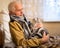 Old gray haired man in sweater holds scottish fold cat