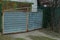 Old gray metal gate and part of a green fence