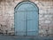 Old gray wooden double door in an ancient authentic stone wall. Gothic style Fortress. Stone medieval buildings