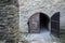 Old gray wooden double door in an ancient authentic stone wall. Gothic style Fortress. Vintage