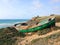 Old green boat resting on the beach. An abandoned boat in the dusk. Abandoned wrecked boat stuck in sand