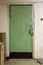 An old green door upholstered with wooden slats