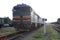 Old green locomotive stands on rails outside the city.