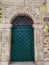 Old green metal door with a lattice in an ancient round arch