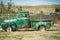 Old Green Pickup behind a chain link Fence