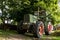 Old green tractor under a tree on a farm, selected focus, narrow