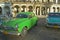 Old green and turquoise American cars are parked in front of old buildings in Old Havana, Cuba