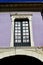 Old green wooden window in a violet wall with silver iron handrail. Pontevedra, old town, Spain.