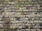 Old grey damp stone wall made of large regular blocks covered in patches of moss