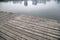 Old grey pier and reflection of buildings on river