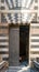 Old grunge decorated bronze-plate door surrounded by striped black and white marble decorations