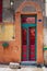 Old grunge decorated door painted in green and red vibrant colors on orange painted stone wall