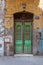 Old grunge green decorated painted door on dirty yellow painted stone wall