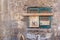 Old grunge window with closed green broken shutters on dirty bricks stone wall