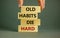 Old habits die hard. Wooden blocks with words `Old habits die hard`. Beautiful grey background, male hand. Copy space. Business