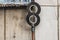 An old hand-made metal television antenna of two metal discs is on the gray wall of a house near the window