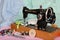 An old, hand sewing machine with a needle, retro coils with colored threads, bright buttons and pieces of colored cotton fabric