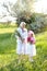 Old happy granny standing with little granddaughter and keeping flowers.