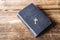 Old hard covered holly Bible and golden crucifix on a wooden background.