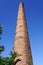 An old high factory chimney against a blue sky