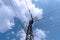Old high voltage electric power tower against blue sky and fluffy clouds