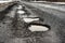 old highway with holes and snow. Landscape road potholes in cloudy winter weather. concept absence of timely repair of highway.