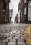 Old historic cobbled high street with selective focus on cobble stones with yellow line painted on winding road leading up