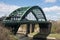 Old historic Victorian metal arched road bridge crossing spanning a river with blue sky