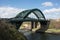 Old historic Victorian metal arched road bridge crossing spanning a river with blue sky