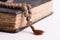 Old holy book and rosary of a priest on a light background