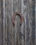 Old horse horseshoe symbol of good luck hanging on a rusty nail on a wooden door