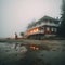 Old hotel near the ocean in Alaska or other northern country. Empty gloomy beach. Misty rainy evening. Generative AI