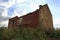 an old house falling apart, standing somewhere in the fields