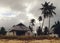 Old house on sandy beach with palms trees