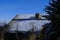 Old house tiled roof in mountains with chimney covered with snow across blue sky.