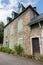 Old house with windows, green shutters and wooden door. Traditional exterior of rural house. Facade of medieval stone building.