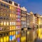 Old houses of Amsterdam. The houses stand in the water and have a beautiful reflection. Touristic district Damrak. These houses