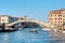 Old houses, moored boats and pedestrian bridge across canal in Venice, Italy.