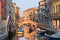 Old houses, moored boats and pedestrian bridge across canal in Venice, Italy. Tourists are returning to Venice, but far