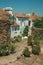 Old houses with whitewashed wall in an alley with flowers