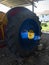 An old huge farmer tractor blue wheel with a sunbeam in middle