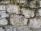 Old huge stone rocks making a wall as a traditional masonry with grass and other green plants sticking out with signs of age and