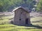 An old hut in the middle of a meadow made of stone and thatch