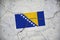 An old image of the flag of Bosnia and Herzegovina on a wall with a crack