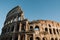 Old imperial coliseum facade architecture on turquoise sky,people visitors,rome