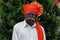 Old Indian grandfather wearing orange color turban and giving pose for photo